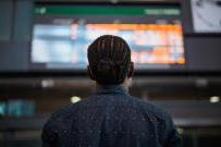 man in control room looking up at large screen depicting various data